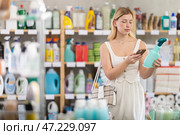Girl buyer scans qr code on glass cleaner spray label. Стоковое фото, фотограф Яков Филимонов / Фотобанк Лори