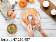 Женщина посыпает сахарной пудрой вкусные тыквенные оладьи на тарелке, вид сверху. Стоковое фото, фотограф Pixel_shot / Фотобанк Лори
