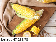 Доска со свежими кукурузными початками на столе. Стоковое фото, фотограф Pixel_shot / Фотобанк Лори