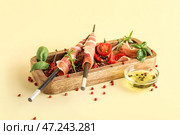 Деревянная доска с вкусным хамоном, специями и миской масла на цветном фоне. Стоковое фото, фотограф Pixel_shot / Фотобанк Лори
