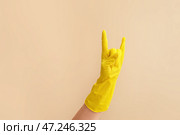 Рука в резиновой перчатке показывает жест «дьявольские рога» на цветном фоне. Стоковое фото, фотограф Pixel_shot / Фотобанк Лори