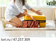 Туристка пытается закрыть чемодан с кучей вещей. Стоковое фото, фотограф Pixel_shot / Фотобанк Лори