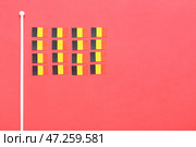 Маленькие национальные флаги Бельгии на красном фоне. Стоковое фото, фотограф Pixel_shot / Фотобанк Лори