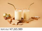 Стаканы вкусного коктейля из гоголя-моголь, елочные шары, печенье и специи на цветном фоне. Стоковое фото, фотограф Pixel_shot / Фотобанк Лори