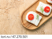 Деревянная доска вкусных сухариков со сливочным сыром и помидорами на цветном фоне. Стоковое фото, фотограф Pixel_shot / Фотобанк Лори