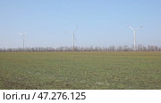Wind turbines spin energetically against a blue sky, harnessing renewable energy in the countryside field on spring. Supporting farmers through innovative practices. Green and renewable power concept. Стоковое видео, видеограф Ирина Михайличенко / Фотобанк Лори