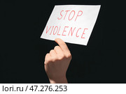 Женская рука держит бумагу с текстом ОСТАНОВИТЬ НАСИЛИЕ на темном фоне. Стоковое фото, фотограф Pixel_shot / Фотобанк Лори