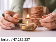 Женщина сжигает веревку для упаковки рождественского подарка за столом, крупным планом. Стоковое фото, фотограф Pixel_shot / Фотобанк Лори