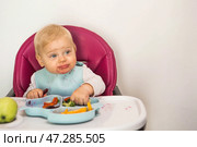 Baby food. The first meal. Feeding the baby. A cute little kid eats vegetables. Healthy food. The child is sitting on a high chair for feeding. Fresh vegetables and fruits. Стоковое фото, фотограф Photojuli / Фотобанк Лори