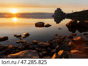 Spring landscape of Baikal Lake at sunset in May. View of Shamanka rock or Burkhan cape, Small Sea and stone beach of Olkhon Island at dusk in the light of the setting sun. Beautiful calm landscape. Стоковое фото, фотограф Виктория Катьянова / Фотобанк Лори