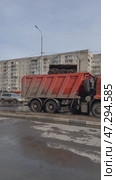 ANGARSK, IRKUTSK REGION, RUSSIA - March 20, 2025: Vertical video of spring cleaning of city roads. Road workers use backhoe loaders to collect icy mud from road and unload it into dump truck for removal. Редакционное видео, видеограф Виктория Катьянова / Фотобанк Лори