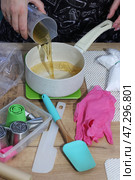 A woman is pouring apple juice into a saucepan. She is preparing syrup for homemade marshmallows. Nearby on the table are zefir-making tools. Pastry tips for creating marshmallow flowers. Стоковое фото, фотограф Vadzim Yakubovich / Фотобанк Лори