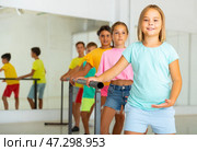 Smiling tween girl practicing classic dance moves near ballet barre. Стоковое фото, фотограф Яков Филимонов / Фотобанк Лори