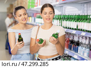 Young women discussing choice of alcoholic drinks in supermarket. Стоковое фото, фотограф Яков Филимонов / Фотобанк Лори
