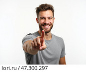 Smiling Man Gestures Playfully While Pointing Forward in a Bright Studio Environment During a Photo Session. Стоковое AI-изображение, AI-художник Sergey Grishin / Фотобанк Лори