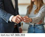 A Real Estate Agent Hands Over House Keys to a New Homeowner in a Modern Apartment, Celebrating a Successful Property Transaction. Стоковое AI-изображение, AI-художник Sergey Grishin / Фотобанк Лори