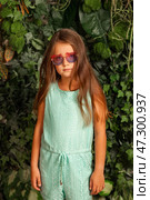 Seven Year Old Girl Model Poses With Confidence in a Green Outdoor Setting Wearing Stylish Glasses. Стоковое фото, фотограф Aleksandr Golubev / Фотобанк Лори
