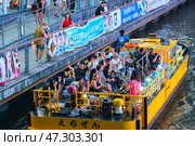 Osaka, Japan - Sep 21 2024, view of the canal in Dotonbori district, along which a yellow boat with a group of tourists sails along the corniche with people, at night, with illumination Osaka, Japan. Редакционное фото, фотограф Сергей Богомяко / Фотобанк Лори