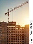 Construction Site at Sunset With Crane and Workers Engaged in Building Activity. Стоковое фото, фотограф Aleksandr Golubev / Фотобанк Лори