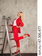 Confidence Shines as a Stylish Woman Poses on a Ladder in a Vibrant Red Outfit. Стоковое фото, фотограф Aleksandr Golubev / Фотобанк Лори