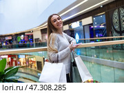 Smiling Woman Enjoys Shopping in a Lively Mall Filled With Vibrant Stores and Activities. Стоковое фото, фотограф Aleksandr Golubev / Фотобанк Лори