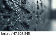 Water droplets collect on a textured black surface in a dimly lit urban setting during early morning hours. Стоковое AI-изображение, AI-художник Сергей Толмачёв / Фотобанк Лори