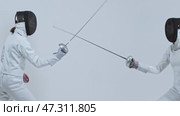 Fencing training in the white studio between two young fencers in white suits. Стоковое видео, видеограф Константин Шишкин / Фотобанк Лори
