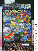 Osaka, Japan - Sep 22 2024, panoramic view of the facade of hotel building completely covered with a variety of graffiti and street art, on corniche of Dotonbori Canal, at nighttime, Osaka, Japan. Редакционное фото, фотограф Сергей Богомяко / Фотобанк Лори