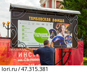 Рабочий вешает афишу с расписанием театральных спектаклей (2024 год). Редакционное фото, фотограф Вячеслав Палес / Фотобанк Лори