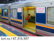 Osaka, Japan - Sep 23 2024, Panoramic view of the electric train carriage with a sign “women only” with the door open, a lonely woman is sitting inside and looking at his phone, Osaka, Japan. Редакционное фото, фотограф Сергей Богомяко / Фотобанк Лори