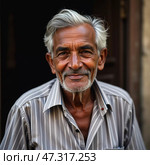 An elderly man with silver hair stands at his doorstep, displaying a kind smile that reflects years of wisdom. The tranquil ambiance of the Indian village surrounds him, evoking stories untold. Стоковое AI-изображение, AI-художник Юлия Петровская / Фотобанк Лори