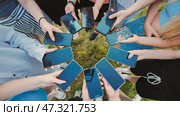 Group of students standing in a circle in the park, holding smartphones with blank screens while enjoying the outdoors together. Стоковое фото, фотограф Mikhail Davidovich / Фотобанк Лори