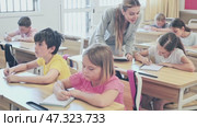 Diligent tweens studying in classroom, listening to lecturer and writing in notebooks. Стоковое видео, видеограф Яков Филимонов / Фотобанк Лори
