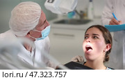 Mature man doctor dentist in white coat examines oral cavity of girl patient in dentistry. Стоковое видео, видеограф Яков Филимонов / Фотобанк Лори