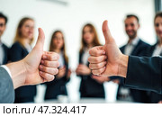 Hands giving thumbs up gesture in focus with business professionals standing in blurred background showing approval, success, teamwork, unity, support, collaboration, and positivity. Стоковое AI-изображение, AI-художник Павел Муравьев / Фотобанк Лори