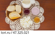 Video of delicious country breakfast with white bread and fresh dairy products - cottage cheese, yogurt, milk on hand-knitted lace napkin on wooden table. Rustic still life. Flat lay, close-up, top view. Стоковое видео, видеограф Виктория Катьянова / Фотобанк Лори