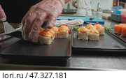 Preparing sushi with fresh ingredients in a busy kitchen setting during midday hours. Стоковое видео, видеограф Сергей Толмачёв / Фотобанк Лори