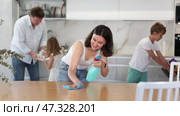 Pleased mother cleansing the table, her husband, son and little daughter helping in tidying the kitchen. Стоковое видео, видеограф Яков Филимонов / Фотобанк Лори