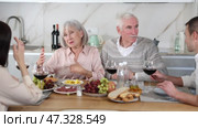 Happy senior parents and young couple talking while drinking wine sitting around kitchen table. Стоковое видео, видеограф Яков Филимонов / Фотобанк Лори