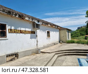 White plastered walls, a thatched roof (or imitation of it), simple wooden windows, an air conditioner on the wall — all this creates an atmosphere of rural comfort and authenticity.In the background are green hills, forest and mountains, which give the place privacy and natural beauty. Probably, this place is somewhere in Crimea or in the south of Ukraine, not far from tourist routes and attractions. Стоковое фото, фотограф Анна Кривицкая / Фотобанк Лори
