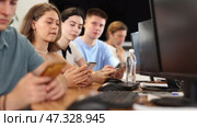 At computer class, young girl student sits with mobile phone and listens admiringly to teacher. Стоковое видео, видеограф Яков Филимонов / Фотобанк Лори