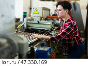 Skilled farmer woman working with automatic filling and seeding line for growing containerized seedlings of decorative plants in greenhouse. Стоковое фото, фотограф Яков Филимонов / Фотобанк Лори