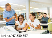 Mature annoyed male interrupts noisy female students. Стоковое фото, фотограф Яков Филимонов / Фотобанк Лори