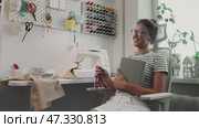 Woman in cozy home sewing studio looks over sketches and measurements in preparation for creating custom garment. Creative process combines precision, craftsmanship, and love of handmade fashion. Стоковое видео, видеограф Енваев Андрей / Фотобанк Лори