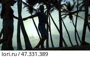 Silhouettes of lovers on the background of palm trees and sunset. Стоковое видео, видеограф Mikhail Davidovich / Фотобанк Лори