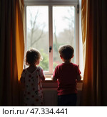In the soft light of dawn, two children stand side by side at a window, their curiosity piqued by the sights outside. They watch the gentle movement of nature Generative AI. Стоковое AI-изображение, AI-художник Юлия Петровская / Фотобанк Лори