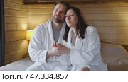 Mature couple in a white bathrobes hugging each other kissing at home bedroom. Intimate Moment. Tender embrace shared between a loving middle age man and woman, husband and wife. Deep love. Vacation. Стоковое видео, видеограф Марина Демидюк / Фотобанк Лори