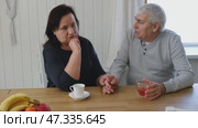 Old couple have breakfast sitting at the kitchen table, drink coffee. Embracing elderly man and woman. Senior couple together marriage in retirement talking with each other. Enjoying the pleasantries. Стоковое видео, видеограф Марина Демидюк / Фотобанк Лори