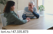 Old couple have breakfast sitting at the kitchen table, drink coffee. Embracing elderly man and woman. Senior couple together marriage in retirement talking with each other. Enjoying the pleasantries. Стоковое видео, видеограф Марина Демидюк / Фотобанк Лори