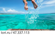 Child jumps into turquoise water from wooden dock on sunny day. Ребенок прыгает с деревянного причала в ярко-бирюзовую воду под ясным голубым небом. Брызги воды создают радостную атмосферу в солнечный день на берегу моря. Стоковое AI-изображение, AI-художник Katsiaryna Repich / Фотобанк Лори
